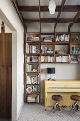 One of the family’s favorite rooms in the house is the library. Young’s wife is an avid reader and founded a children's literacy nonprofit here in Orlando. The couple needed a space for everyone’s books, and finding a place where they could display them side-by-side was important. 
The bookshelf, part of a larger shelving grid, is built around a bright yellow piano. The piano was Young’s wife's when she was growing up and it was originally a very boring, oak brown. “We wanted it to be the signature feature of the room and painting it yellow is always a fun surprise when you walk in the room. This is the room you can find us in most nights playing board games, playing piano, and drinking wine.”