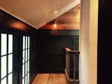 Photo shows the blending of wide plank oak flooring, charcoal trim features, and white tongue and groove bead board ceiling.  Vintage Brass Sconce.  