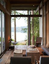 The living room’s large wall of glass frames a view of the adjoining grassy field and Puget Sound, visually blending indoors and outdoors. 