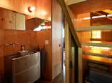 Agate Pass Cabin | In the powder room, a former hospital cart was redesigned into a stainless steel sink and cabinet | Glass relites in the staircase risers act as a window providing natural light and views into the garden.