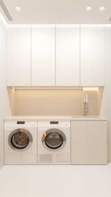Modern laundry room with seamless white cabinetry and soft lighting