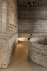 A bold design showcasing raw concrete in the bathroom with a sculptural bathtub and minimalist lighting. #mb3h #bathroomdesign #concreteinteriors #minimaliststyle