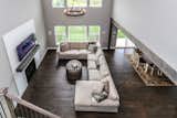 Living Room, Medium Hardwood Floor, Sectional, Ceiling Lighting, and Standard Layout Fireplace Dramatic and Airy Two Story Family Room with Shiplap Inspired Fireplace with Beam Styled Mantle.  Photo 17 of 17 in The Parker II Eco-Smart Model Home by DJK Custom Homes, Inc.