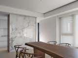 Dinning space and kitchen defined by a storage unit with stone facade.