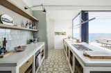 Kitchen, Concrete Counter, Ceramic Tile Floor, Refrigerator, Wall Oven, Porcelain Tile Backsplashe, Wall Lighting, Range, and Drop In Sink  Photo 8 of 16 in A Careful Renovation Brings New Life to a Family’s Heritage Home on the Spanish Coast