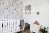 According to Wijaya, “The design for the nursery was inspired by my recent trip to Australia. I wanted to make this room feel a bit whimsical. We used Chasing Paper’s removable wallpaper because we loved the striking pattern (and it is easy to install and can be easily removed). We used cafe doors for the closet doors because we wanted to elevate and add uniqueness to the room. The white sconce hanging on the wall is by MOOI.”