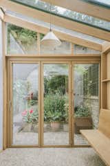 The glass house interior features a timber terrazzo floor made from recycled waste wood for a sense of playfulness, warmth, and harmony with the oak frame.