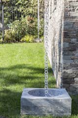 An aluminum rain chain diverts rain water into a custom-made board form concrete basin, which then irrigates the terraced gardens.