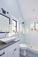 A skylight and vaulted ceiling in the bathroom fill the space with natural light, washing over cool, calming tones of light blue and gray. 