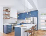 Kitchen - The kitchen bookends the great room with a rich blue. A skylight over the island filters natural light deep into the space. 