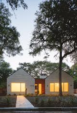 Front Elevation - At night, the large windows that carve into the two stone wings give the house a radiant, inviting presence to the surrounding neighborhood.