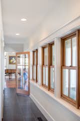 A row of single hung wood windows defines the entry hallway with views towards the front porch.