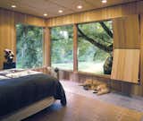 The Master Bedroom features wide expanses of windows overlooking the 2-acre garden. The adjacent original wood "ventilator" hides a series of wood louvers that can be exposed or closed depending on the air flow need. The concrete floor features radiant heat, further visual warmth is supplied by the room's wood paneled walls and ceiling.