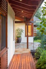 The entry displays a diversity of wood species: Mahogany panels at the wall, a Cedar slat walkway and Douglas Fir framing members.  A copper rain chain diverts rain water to the entry planting bed.  Photo 8 of 11 in Love It or Hate It? Rain Chains by Dwell from Lakeside House