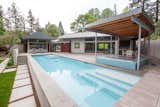 The pool is surrounded by a generous terrace and features a covered hot tub and seasonal kitchen.   Photo 12 of 12 in Cedar Mills House by Telford+Brown Studio Architecture