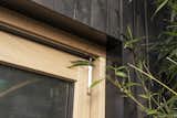 A close up view of the charred timber facade, the oak framed door and the bespoke steel frame surrounds