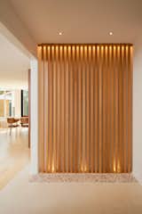 An entry screen wall with concealed lighting resembles the Shoji art of paneling.
