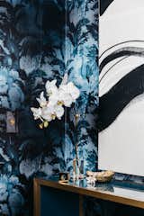 Brass details and accessories compliment the bright blue wall covering and console table.