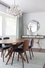 To complement the homeowners statement pieces, like the chandelier, and to keep the space feeling connected to the rest of the house, the furnishings and silhouettes were kept streamlined. Wood tones correlate with the adjacent rooms, creating a cohesive look.