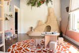 Inspired by safari photos of sand hills and termite mounds, the wooden play space was custom-made using sheets of plywood and provides an escape from reality. Wooden rings hung from the rafters add another element of play.