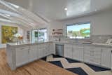 Kitchen, Marble Counter, White Cabinet, Light Hardwood Floor, Recessed Lighting, Refrigerator, Range Hood, Wall Oven, Cooktops, Microwave, Dishwasher, and Undermount Sink  Photo 13 of 25 in Private Modernist Sanctuary! by Malia Camerino