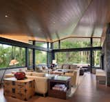 The living room opens, a glass-enclosed perch located at the house’s highest point, connects to nature with views looking into the tree canopy. The floating folded roof plain move through the space.
