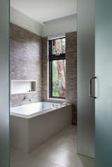 The bathroom was designed with a Limestone floor, Mosaic tile walls with integral niche, and slab tub surround. 