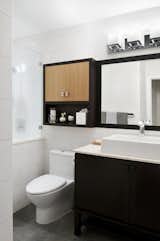 The guest bathroom is more of a minimal, white space, with wood accents to 	bring in the elements of nature. The vanity was purchased from Kohler, but the mirror and cabinetry above was custom designed and built to coordinate with the vanity below, and add storage. The wall tile, although white, has a unique geometric pattern to it which created more interest in the bright space.
