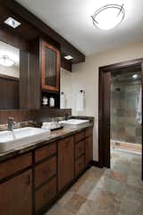 In the master bathroom, we went for a much more earthy, and rustic look. Using a porcelain slate tile with lots of nice variation in it, we made this the element that connected both the vanity area and the shower room, and used it on the floors as well as the walls. The sink vanity was a custom designed and built unit with a Brown Forest Marble top and lots of storage space! Minimal, white vessel sinks completed the look, and added a more modern touch.

The pocket door was added, and stained to match the vanity area. Moving into the shower and toilet room, the main element here was the highly textured and varied tile. We accented this with a teak floor in the shower, and some rustic, live edge wood shelves above the toilet. Again, we used more modern fixtures and lighting to contrast against the rustic materials.
