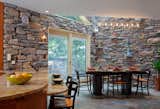This private home is situated on a private street, right on the water, is surrounded by nature. It was important to this family, to bring in the elements of their outdoor patio and garden off the kitchen, into their interior. The stacked stone was the first element that was continued into the space, as well as the real slate flooring throughout the kitchen.  

A custom chandelier was made to go over the eat in kitchen table. Custom built by Michael McHale, this industrial chic chandelier is made up of a mix of pipe and Swarovski crystals. It sits under a skylight above, and reflects colors and light over the table. 