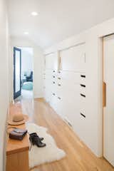 Custom millwork and cabinetry can be a great way to add storage while keeping the hallway looking clean, neat, and bright. Cut-outs in the doors instead of knobs or cabinet handles ensure that hardware doesn't take up any extra space in the narrow corridor.