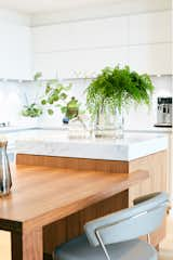 Custom walnut and carrara marble center island acts as a prep space as well as dining table