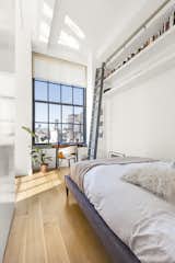 The bedroom previously had floor-to-ceiling shelving with a library ladder. The storage was scaled back with open shelving across the length of the room.