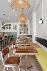 The design feels contemporary yet warm thanks to wicker lighting, colorful artwork, and cozy benches.  
