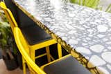 Bright yellow stools with black leather cushions pair well with the natural stone bar. 