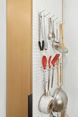 A pegboard hanging along a six-inch wide pantry cabinet pulls double-duty as a drying rack and storage solution.