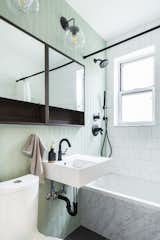 A Ditmas Park, Brooklyn bathroom with a textured tile statement wall and marble-sided bathtub.