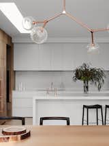 Marble Counter, Range, White Cabinet, Marble Backsplashe, Light Hardwood Floor, Pendant Lighting, Drop In Sink, Windows, and Skylight Window Type  Photo 7 of 10 in A Run-Down Melbourne Bungalow's Makeover Embraces Light and Family Life