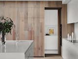 Kitchen, Wood Cabinet, White Cabinet, Marble Backsplashe, Wall Oven, Marble Counter, Range, Drop In Sink, and Light Hardwood Floor  Photo 8 of 10 in A Run-Down Melbourne Bungalow's Makeover Embraces Light and Family Life