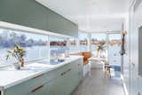 The design of this Australian houseboat features a soft, modern color palette. Here, light sage laminate kitchen cabinets are paired with leather recessed pulls.