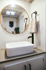 The Mayes did not want to separate the fixtures in the bathroom, so this one hosts the sink, toilet, and a shower. The brass mirror bounces light in the small space.