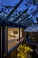 The principal bedroom windows embrace the sandstone rock face. A sloped glass roof shields from rain.