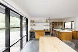 The sink was relocated for functionality, and new windows above it were installed so the owner can look out over the garden while doing dishes. The perimeter counters are composed of custom-made 15-ply birch with oak butcher block-style veneer, while the island is topped with Caesarstone. A new bar area with two under-counter fridges and a pop-up TV replaced a pony wall from the '70s.