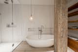 The walls in the shower and behind the tub are clad in slabs of Bianco Dolomiti marble. The floors are the same reclaimed bleached white oak used throughout the house. The light over the tub is the owner's, sourced from souks in Marrakech.