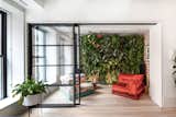 The new lounge space connects to the living room via a sliding steel-and-glass door, and accommodates the homeowner’s gardening hobby via a striking green wall.