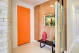 In the entry, an orange door and period-appropriate privacy screen set the tone.
