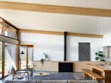 In the living room, the horizontal lines of the timber beams at the ceiling echo the bespoke cabinetry that surrounds the gas fireplace. The dining room pendant is the Gubi Semi Pendant.