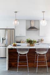 Naber revamped the kitchen with flat-front white cabinets, durable solid surface Cosentino counters by Dekton, and West Elm pendents for a light and airy destination.
