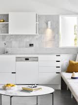 In this Australian kitchen, the open-backed portions of the upper cabinets reveal the marble tile backsplash. The marble backsplash is comprised of two parts: a low marble piece made of the same marble slab as the countertop, and then a square marble tile found elsewhere in the kitchen.