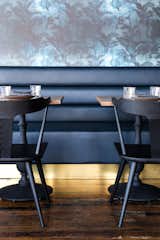 A dark blue leather banquette with a brass kick-plate syncs with the Eskayel wallpaper.